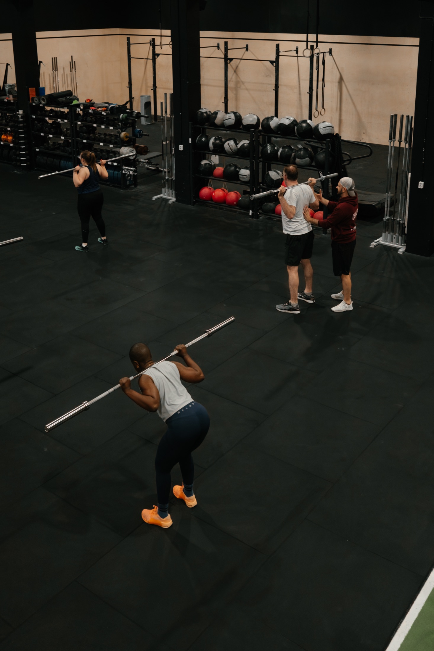 Coach guiding athletes during barbell training